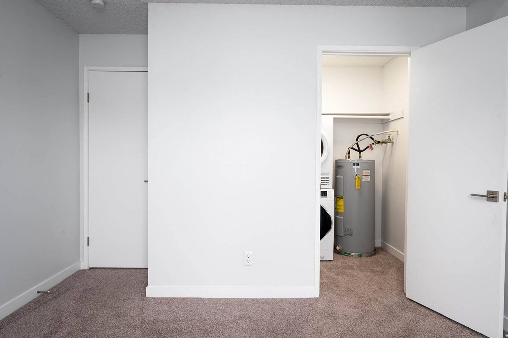 a room with a white wall and a closet and a water heater